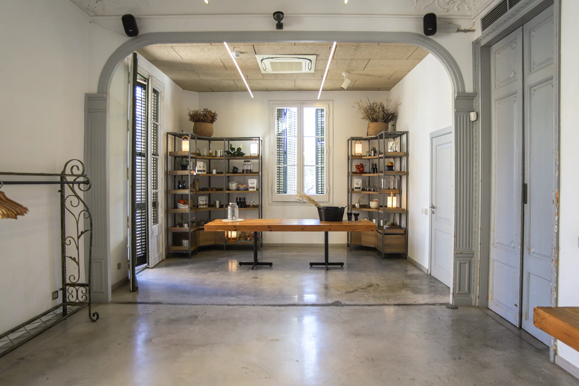 Sala para eventos Barcelona en Barcelona - Cocina vista a través de arco con ollas de cobre, luz natural y mesa de madera