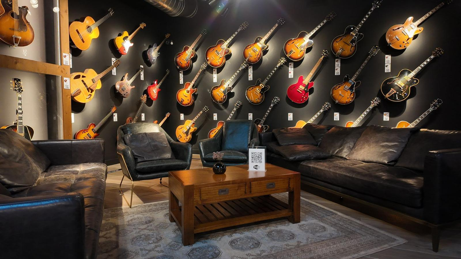 Salón de fiestas Las Vegas en Barcelona - Panorámica con pared de guitarras eléctricas, sofá Chesterfield y pantalla de proyección